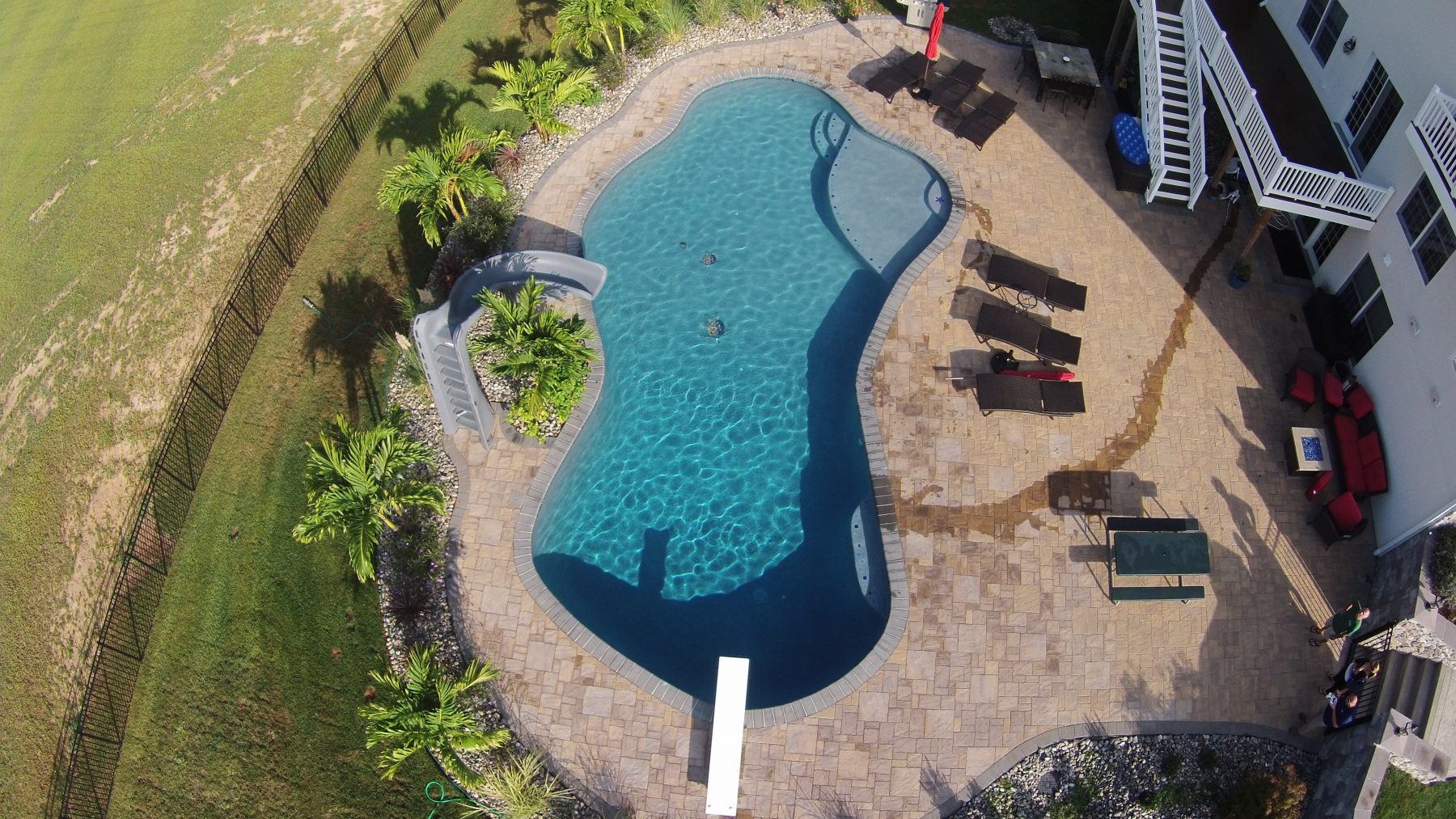 A custom pool with a slide and tanning shelf by Coastal Pools in Centreville, Maryland