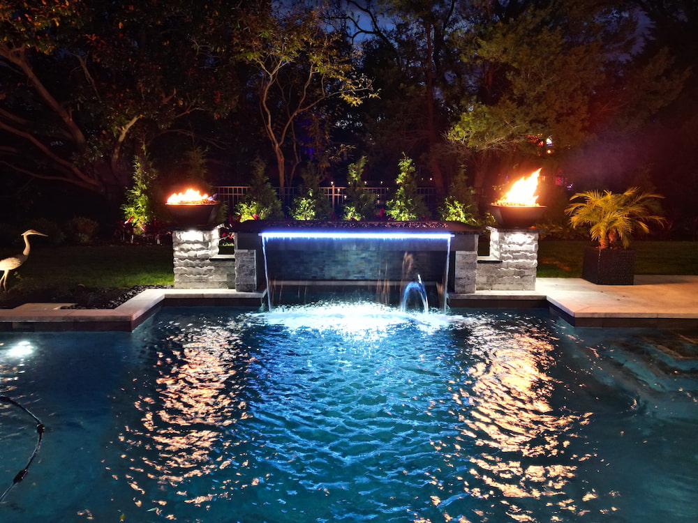 custom pool featuring waterfall and poolside fire features
